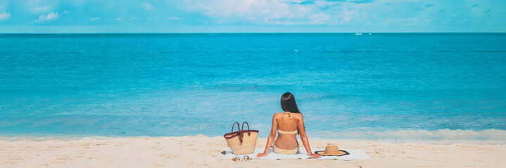 Wall Mural - Beach summer vacation banner relaxing sunbathing woman lying on towel tanning alone panorama travel on blue ocean panoramic header crop.