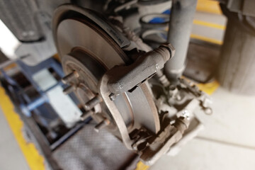 A mechanic repairing, grinding the brake disc and replacing worn out brake pads at an auto repair shop service station - vehicle safety concept