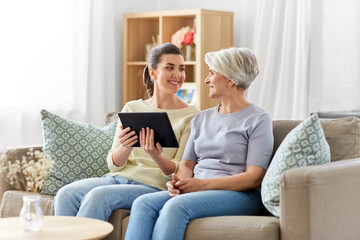 Poster - family, generation and technology concept - happy smiling senior mother and adult daughter with tablet pc computer at home