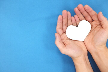 Male hands holding white heart shape. Charity and kindness concept. Top view with copy space.