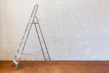 A Construction Ladder Stands On A Wooden Floor.