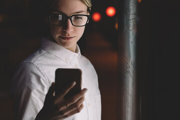 Wall Mural - female standing at interactive kiosk with smartphone in hand. young woman reading information on mob
