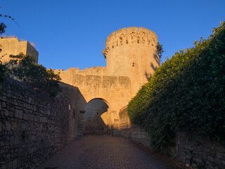 Cobbled street of a medieval village with arch in the walls and tower