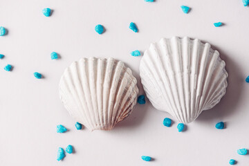 White sea shell surrounded by blue sand on bright background, Summer time concept