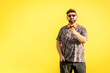 © Sergi - Curvy man with cap, sunglasses pointing forward with yellow background.