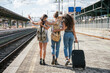 © loreanto - Three young friends women at the station walking and waiting train for their trip in summer with face mask for protection by infection from Coronavirus, Covid-19 - Millennials having fun together