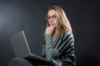 © alex.pin - Segretaria, bionda è seduta nella sua postazione di lavoro di fronte al computer isolata su sfondo nero