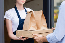 Cropped View Of Man Receiving Pizza Boxes And Packages From Waitress Near Cafe