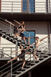 © master1305 - The group of modern ballet dancers performing on the stairs at the city. Fast moving of citylife, grace in daily things around. Graceful and flexible models in sunshine with buildings on background.