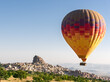 Big colorful hot air balloon flying against Nevsehir town in Cappadocia, Turkey