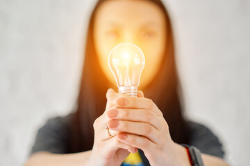 a woman holds an electric lamp that shines with warm light. The concept of a new idea