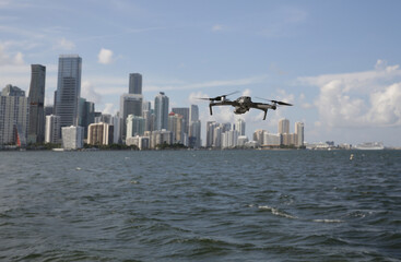 quadcopter or drone in flight against the background of city skyscrapers and water of the sea or river. New technology concept. 