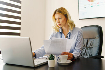 Young beautiful caucasian woman working at office - Female adult checking reports using laptop and hold documents - Secretary or project manager at work - Success struggle effort and routine concept