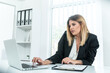 © Bojan Topalovic - Stylish young lady in suit sitting in office and working on laptop.