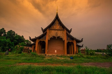 The background of the Wat Pa Kham Charoen is a beautiful old church with a Buddhist statue and a tree-lined temple, with tourists and travelers always making merit in Udon Thani, Thailand.