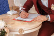 © Екатерина Говорина - The groom signs the marriage registration documents.