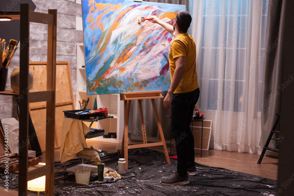 Talented young man painting on large canvas in studio. Modern ...