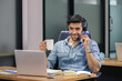 © eakgrungenerd - handsome man speaking microphone with headset looking laptop holding coffee cup at table work in home office, online conference, work new normal.