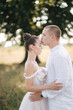 © Aleksandr - Close up portrait of groom kiss bride in forehead in front of big tree. Side view