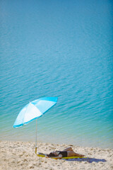 Wall Mural - woman in swimsuit walking by sand beach blue sun umbrella and yellow blanket