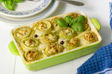 Wall Mural - Baked zucchini rolls with cottage cheese, herbs and sour cream in a ceramic dish