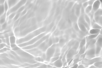 Closeup of desaturated transparent clear calm water surface texture with splashes and bubbles. Trendy abstract nature background. White-grey water waves in sunlight