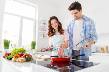 Portrait of two nice attractive cheerful friendly people cooking domestic fresh homemade meal in light white interior kitchen house apartment indoors