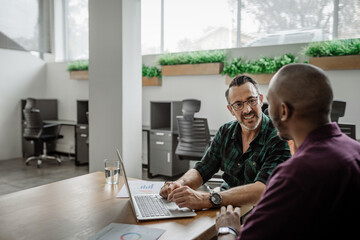 To diverse businessmen working on a laptop at an office table