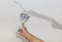 Worker Fixing Cracks On Ceiling, Spreading Plaster With Trowel, Selective Focus
