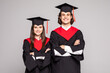 Full length portrait of a young couple posing with their diplomas isolated on white background