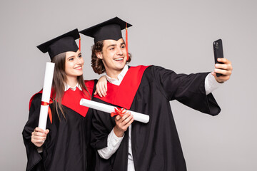 Wall Mural - Male and female student taking a selfie with mobile phone on white background