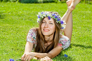 Wall Mural - young woman lying on the grass over green natural background