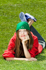 Wall Mural -  young woman lying on the grass wearing color youth clothes, space