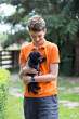 Uśmiechnięty chłopak, nastolatek trzyma na rękach czarnego szczeniaka labrador retriever