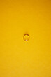 Minimalism composition with one water drop on yellow surface. Optical lens on orange background.