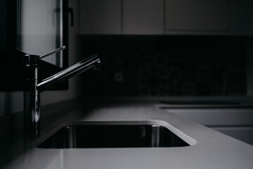 Wall Mural - Dark shot of a silver metallic faucet in a modern kitchen