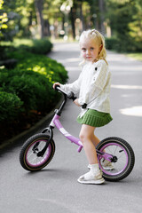 Little blonde girl with a rune in the park in the summer on a walk