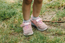Children's Feet In Sneakers On The Grass