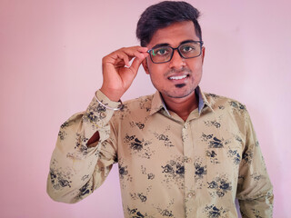 Wall Mural - South Indian handsome man adjusting specs and smiling on pink background