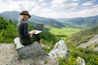 Woman working on her computer on the top of the mountain. Remote work concept.