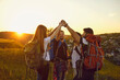 © Studio Romantic - Group of hikers.Team of happy tourists with backpacks raised their hands up in nature at sunset in summer.