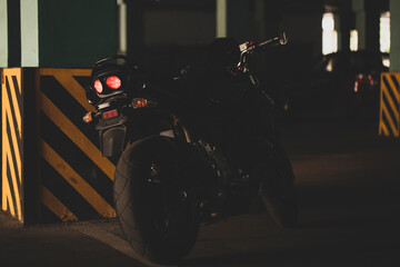 Wall Mural - Black motorcycle on the background of underground parking.