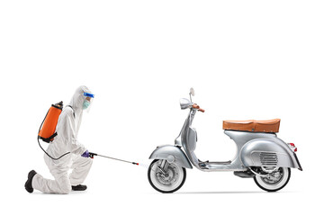 Wall Mural - Specialist in a hazmat suit spraying a disinfectant to a scooter bike