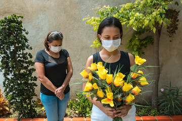 Two people mourning lost ones to coronavirus, wearing face masks