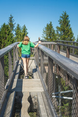 Teenager girl overcoming obstacles and going forward on elevated tree tops walk.  Active relaxation outdoors in nature.