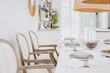 © Photographee.eu - Stylish plates on white table in elegant bright living room interior with wooden chairs