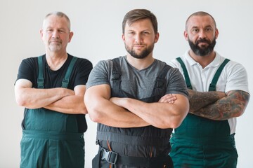 Crew of three professional builder wearing overalls standing in empty interior