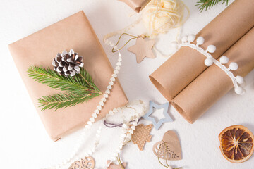 christmas gift box packed in kraft paper and decorated with a fresh spruce branch and a pine cone, natural materials for decorating gifts on a white background, eco friendly christmas concept