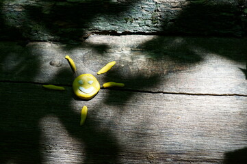 Poster - A figure of a smiling sun on a wooden surface.