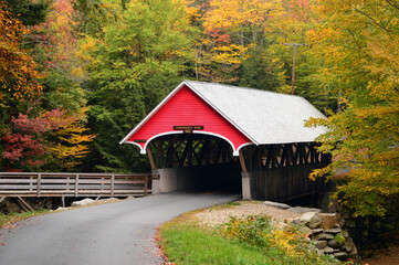 A quaint covered bridge is framed with autumn foliage in New Hampshire